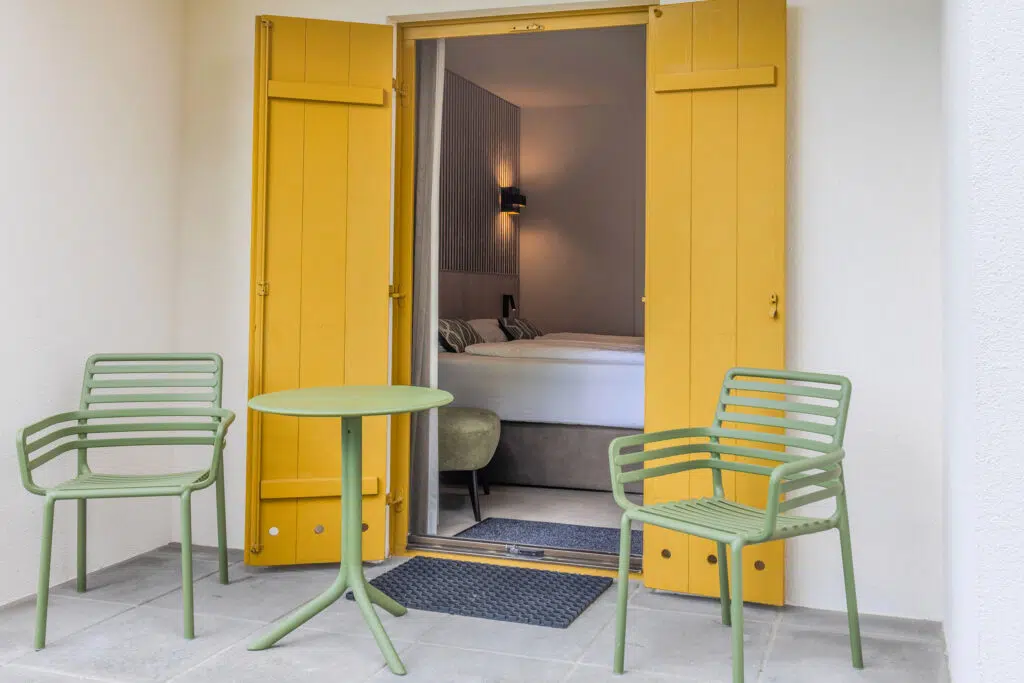 Terrasse mit hellgrünen Gartenstühlen vor gelben Fensterläden, Aldiana Club Ampflwang