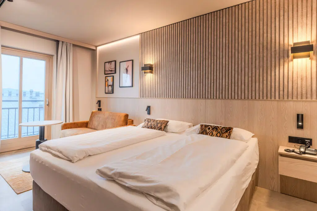 Schlafraum mit Bildergalerie, Wandleuchten und cognacfarbenem Sofa, Aldiana Club Ampflwang