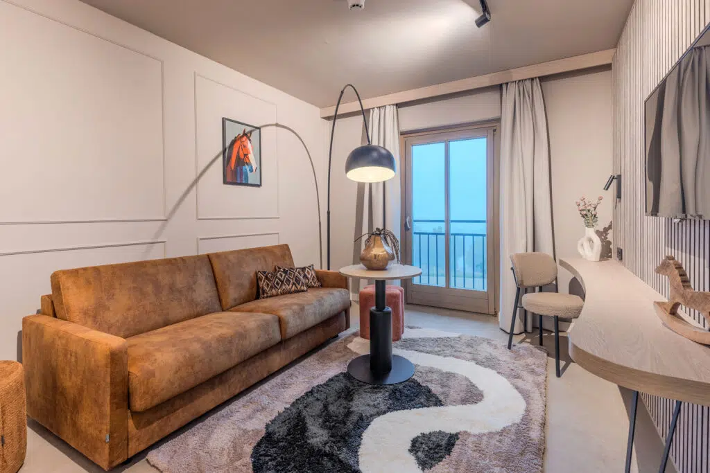 Wohnbereich mit cognacfarbenem Sofa, Bogenlampe und rundem Hochflorteppich, Aldiana Club Ampflwang
