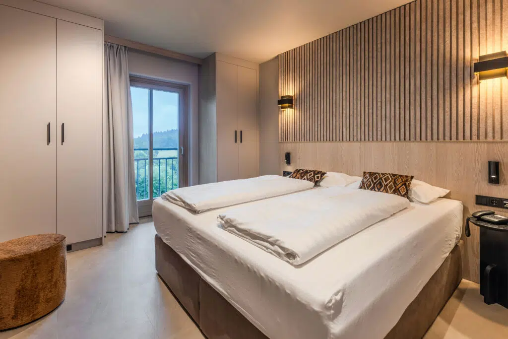 Bett vor Lamellenwand, hoher Schrank und Balkontür zum Wald, Aldiana Club Ampflwang