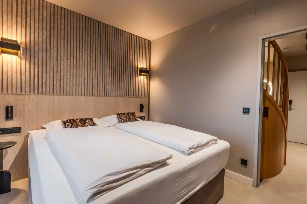 Schlafbereich mit Lamellenwand und geschwungener Holztür zum Flur, Aldiana Club Ampflwang