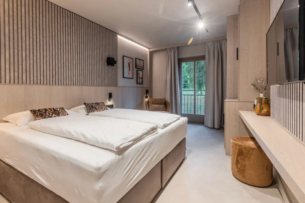 Helles Zimmer mit Lamellenwand, Bilderwand und rundem Hocker an der Konsole, Aldiana Club Ampflwang