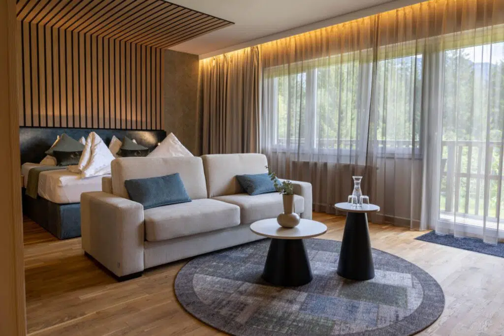 Suite mit cremefarbenem Sofa, runden Beistelltischen und Holzlamellendecke, Aldiana Club Salzkammergut