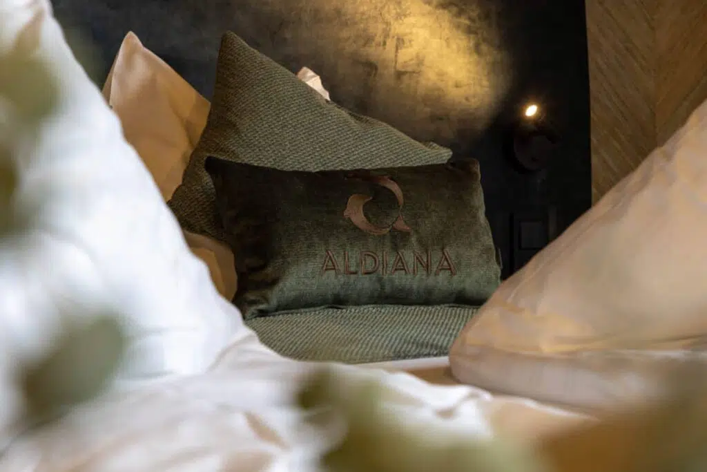 Nahaufnahme eines olivgrünen Kissens mit Stickerei auf weißer Bettwäsche, Aldiana Club Salzkammergut