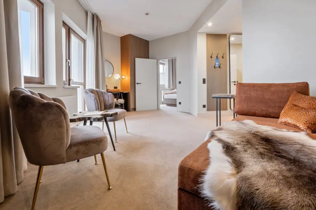 Suite mit samtigen Muschelsesseln, rostfarbenem Sofa und Fellplaid, Aldiana Club Schlanitzen Alm