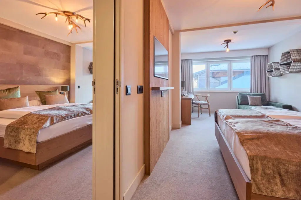 Verbundene Zimmer mit Geweihleuchten, Samtdecken und grüner Bank, Aldiana Club Schlanitzen Alm