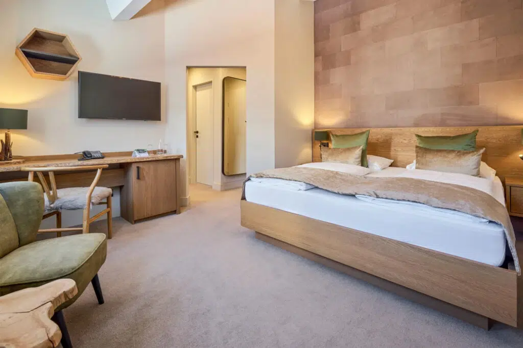 Doppelzimmer mit Arbeitsplatz, grünem Sessel und Wandpaneelen in Lederoptik, Aldiana Club Schlanitzen Alm