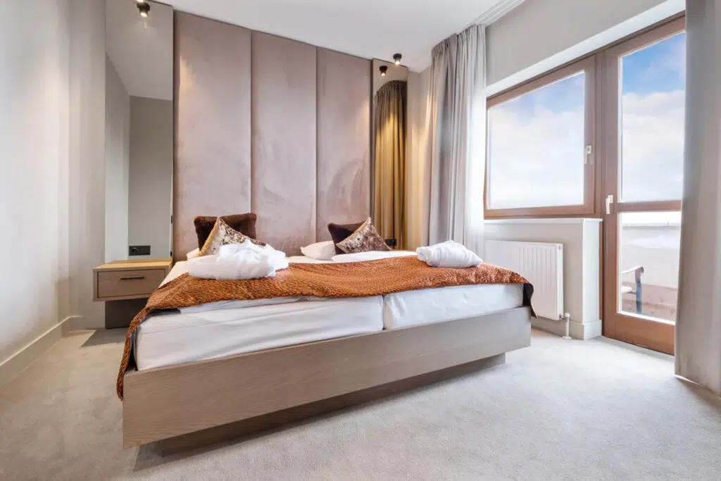 Gepolsterte Wandpaneele hinter dem Bett und orangefarbenes Strickplaid, Aldiana Club Schlanitzen Alm