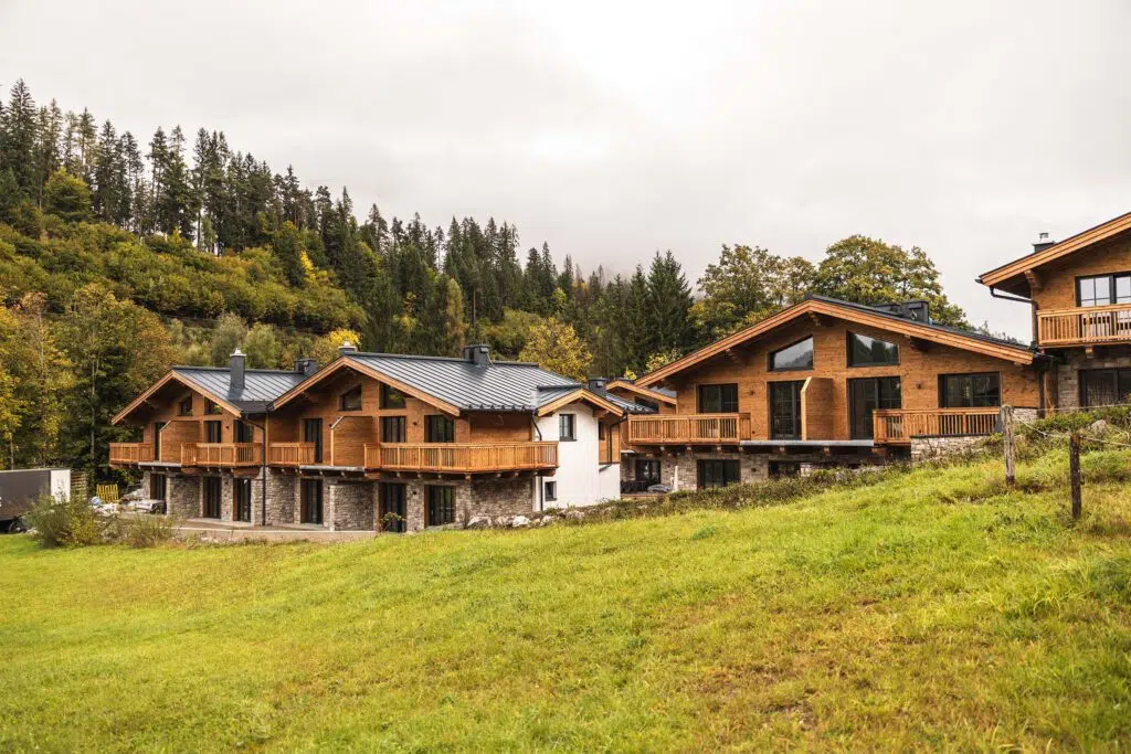Chalets mit Holzfassade, Natursteinsockel und Balkonen am Waldrand, Tauernlodge