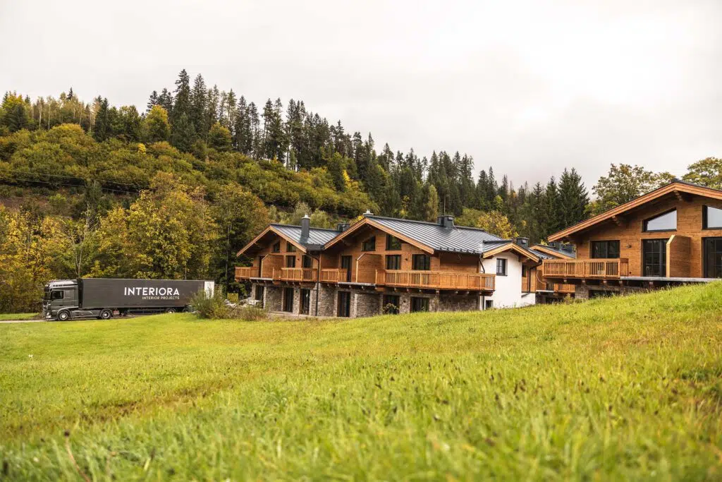 Lkw-Auflieger mit Interiora-Schriftzug neben den Chalets auf der Wiese, Tauernlodge