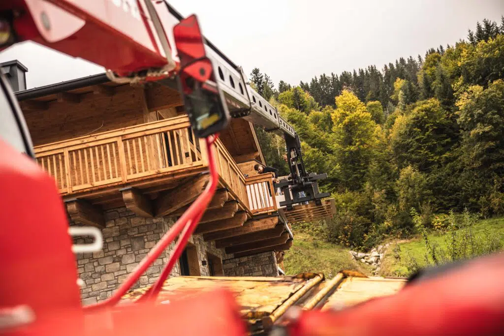 Kran hebt Material auf den Balkon eines Chalets im Rohbau, Tauernlodge