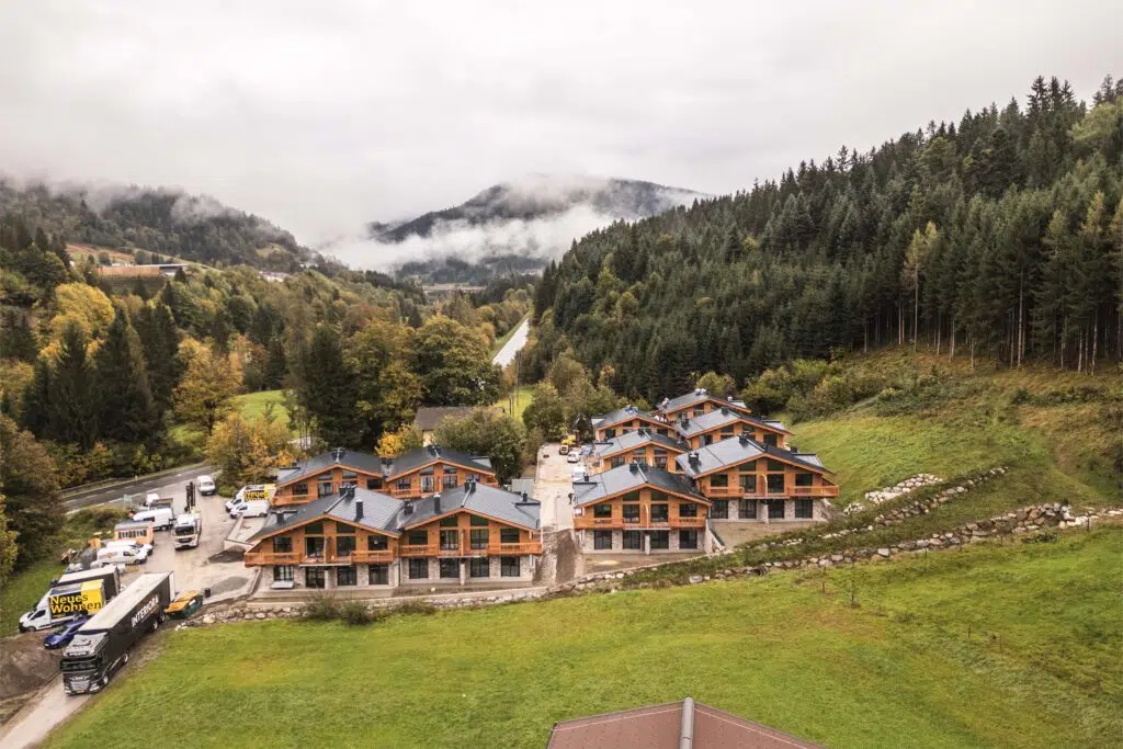 Luftaufnahme der Chalets am Waldrand mit Interiora-Lkw vor der Baustelle, Tauernlodge