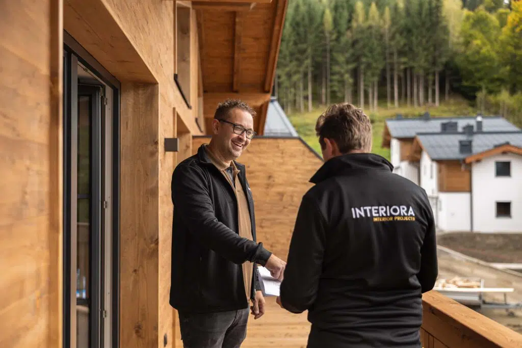 Zwei Mitarbeiter im Gespräch auf dem Holzbalkon eines Chalets, Tauernlodge