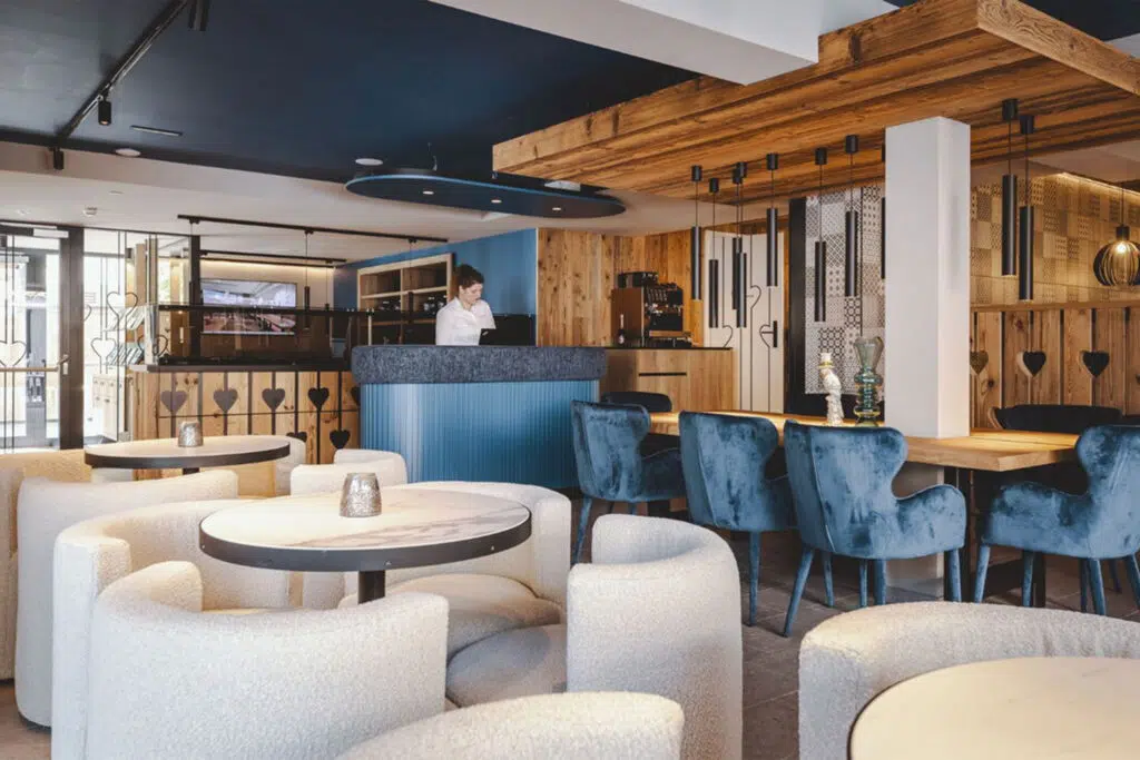 Lobby mit blauen Samtsesseln, cremefarbenen Bouclé-Sesseln und Altholzwänden, The Gast House